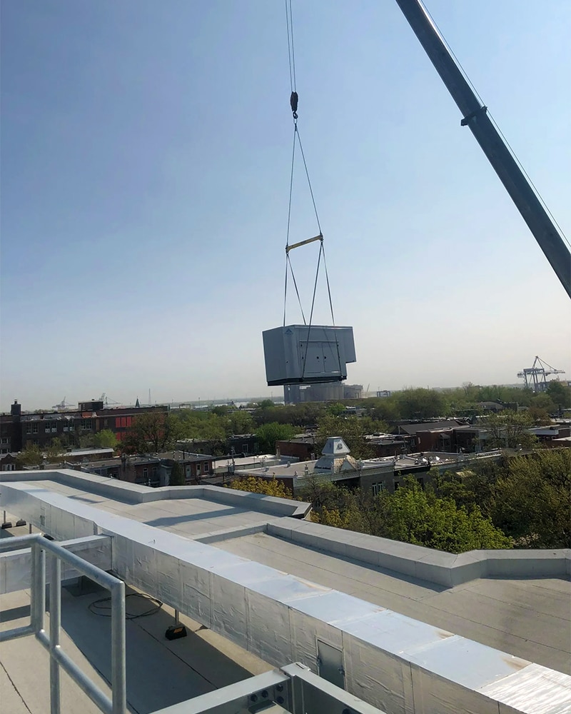 Installation avec une grue d'une génératrice commerciale sur une toiture.